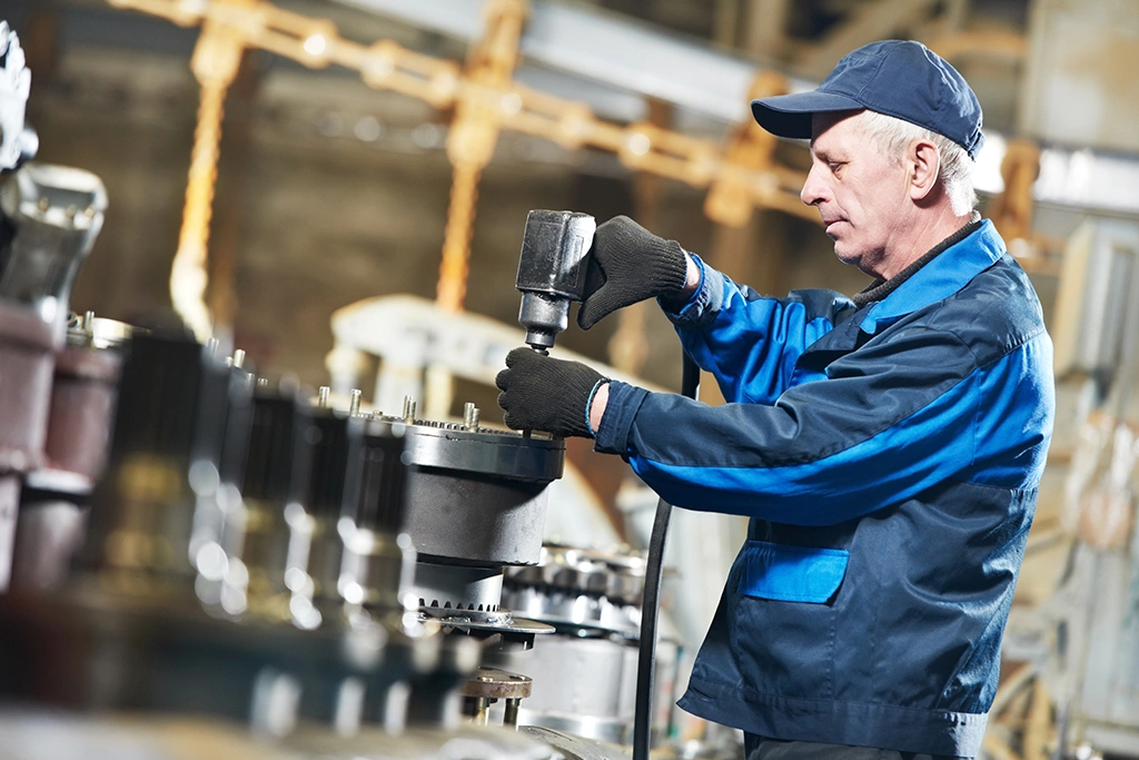 Handwerker in einem Blaumann demontiert eine Industrieanlage