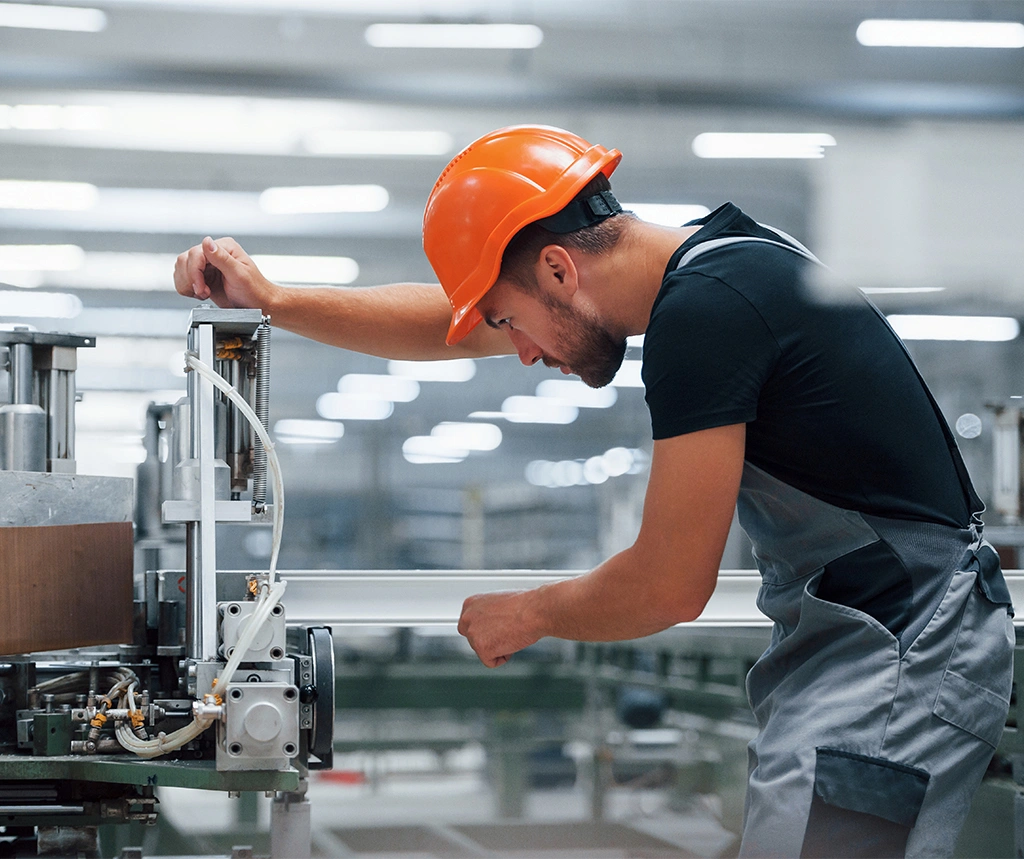 Handwerker mit Sicherheitshelm wartet eine Industrieanlage